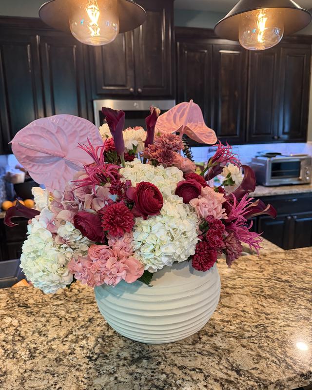 Amor Profundo by Blooms x Mel — Pink anthuriums, red ranunculus, burgundy callas, and hydrangeas in a ribbed ceramic vase