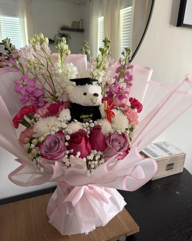Grad Bear Garden by Blooms x Mel — A full garden-style grad bouquet with roses, stock, and mums, crowned with a graduation bear