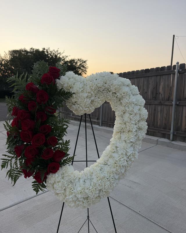 Heart Wreath by Blooms x Mel — An open heart of white carnations with a cascade of red roses and fern, on a standing easel