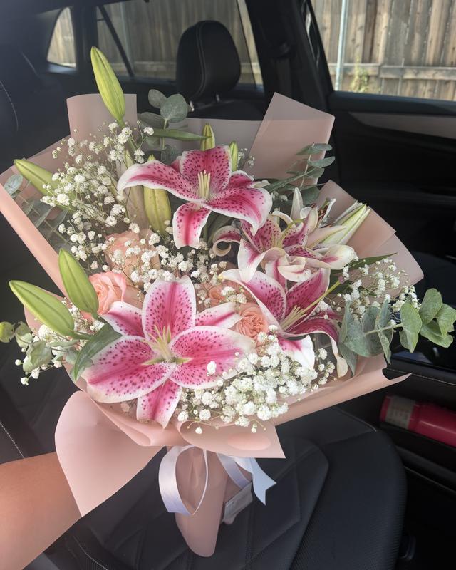 Petite Stargazer Durazno by Blooms x Mel — peach roses with stargazer lilies, baby's breath, and eucalyptus in a soft pink wrap